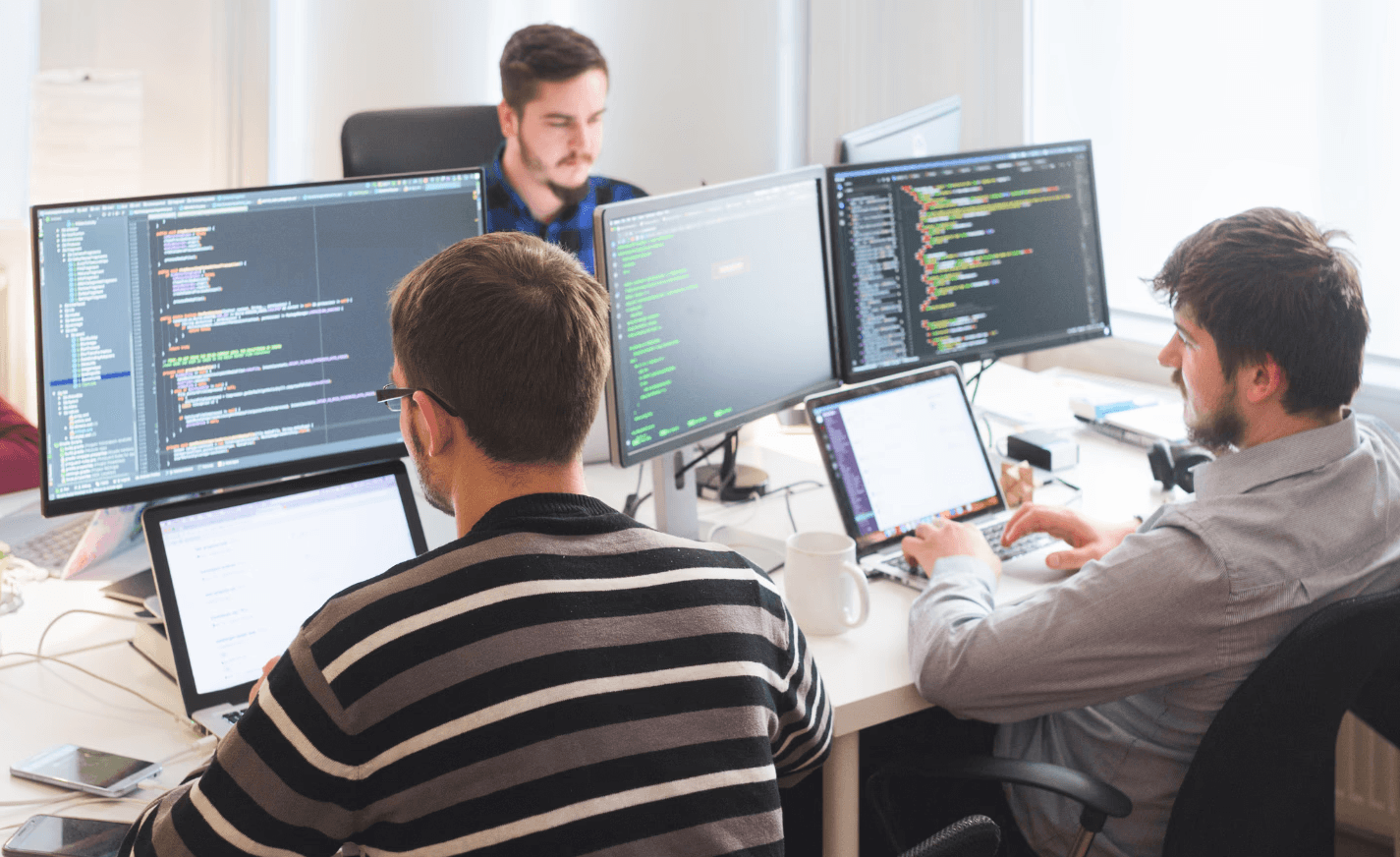 Three people collaborating at a computer, discussing work and sharing ideas on the screen.